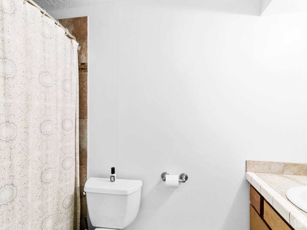 Bathroom with toilet, vanity, and a textured ceiling