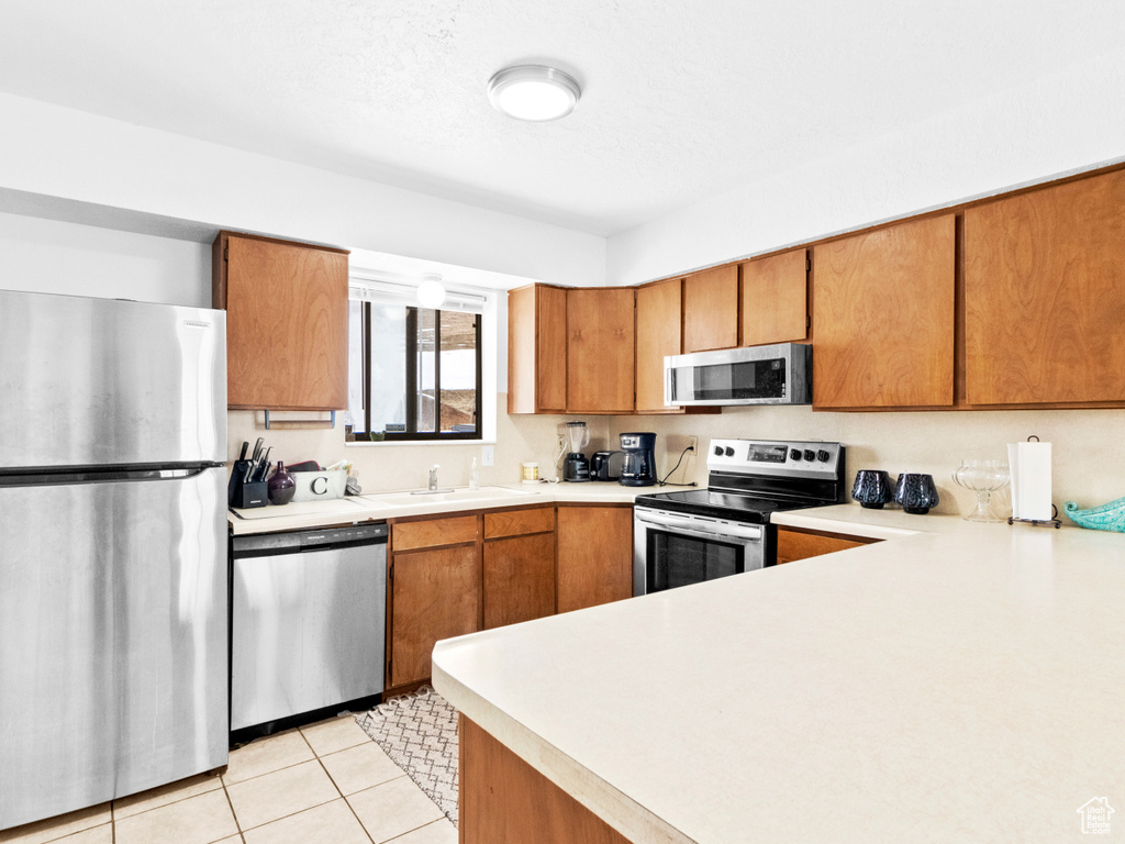 Kitchen featuring sink, appliances with stainless steel finishes, and light tile floors