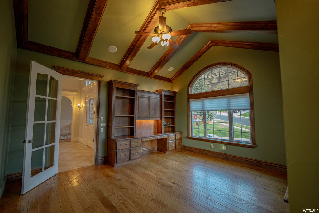 Empty room featuring high vaulted ceiling, french doors, ceiling fan, light wood-type flooring, and beam ceiling