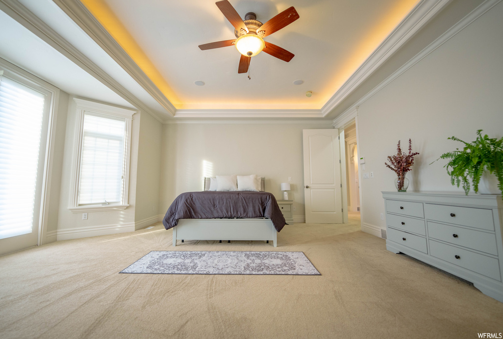 Bedroom with light carpet, a tray ceiling, ceiling fan, and ornamental molding