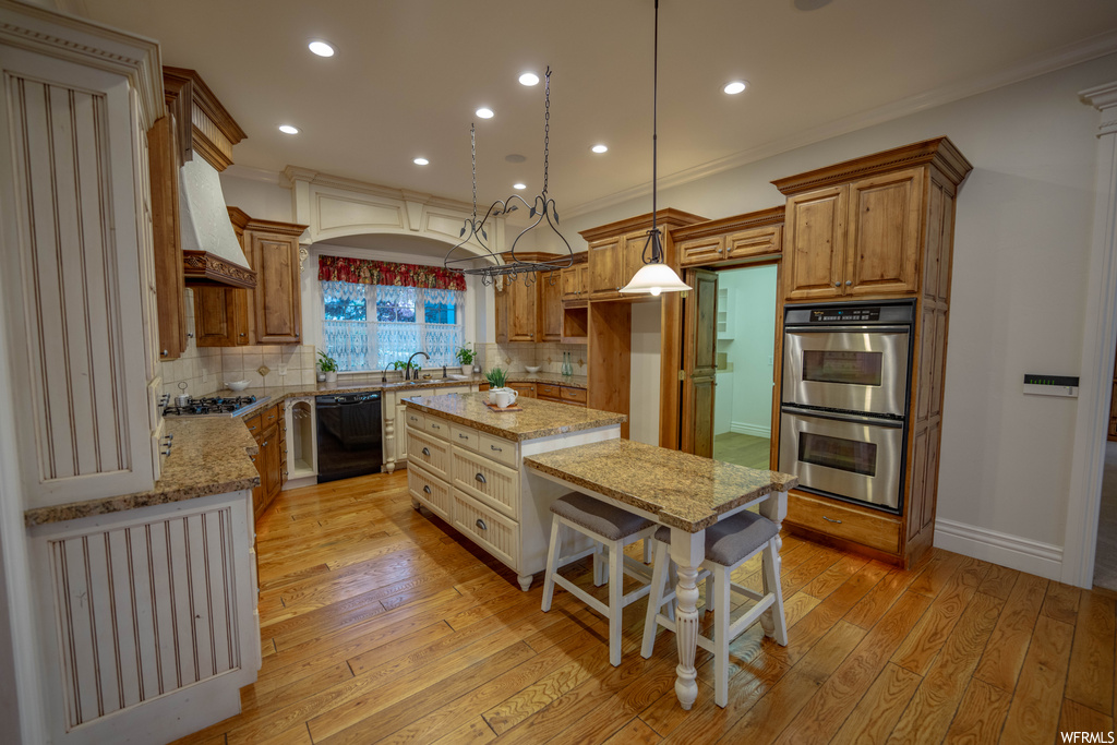 Kitchen with light stone counters, backsplash, a kitchen island, and appliances with stainless steel finishes