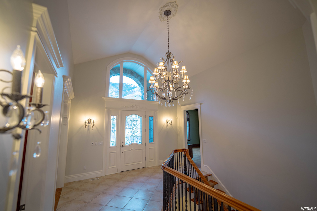 Foyer entrance featuring light tile flooring, a notable chandelier, and high vaulted ceiling
