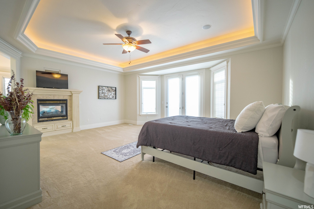 Bedroom with light carpet, a tray ceiling, ceiling fan, and ornamental molding