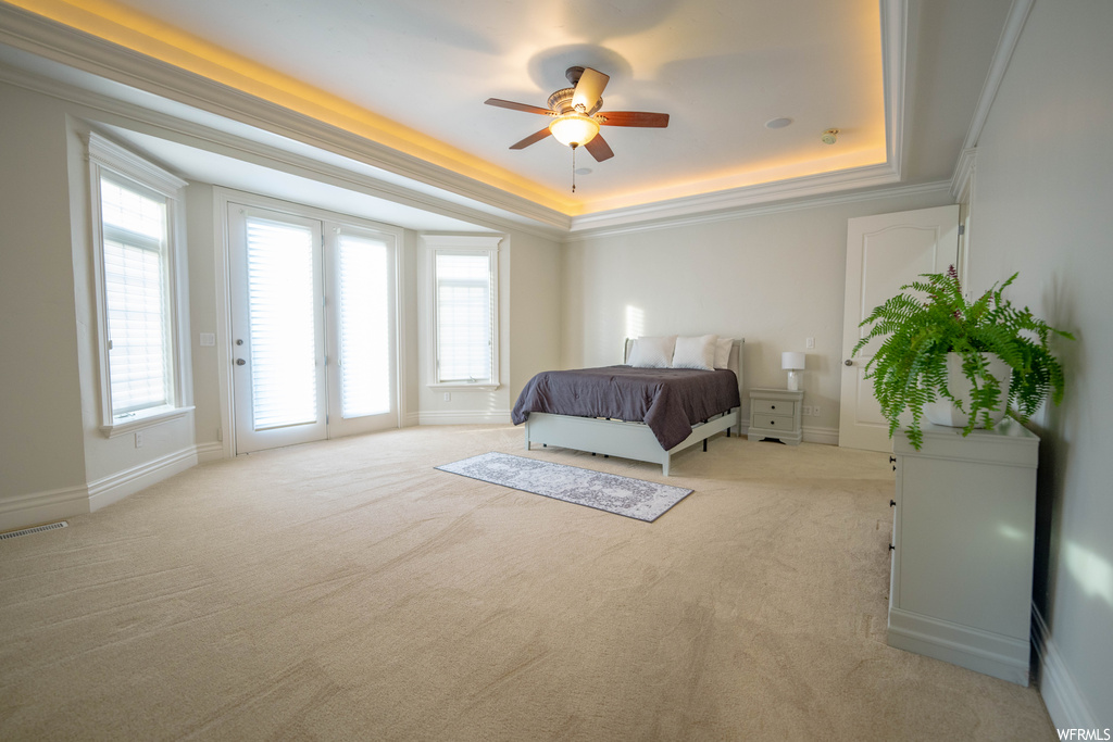Bedroom with ceiling fan, ornamental molding, a raised ceiling, and light carpet