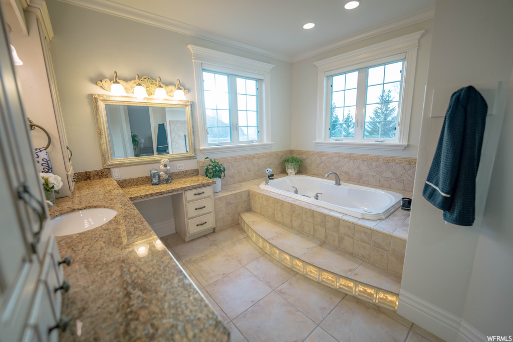 Bathroom with tiled bath, vanity, tile floors, and crown molding