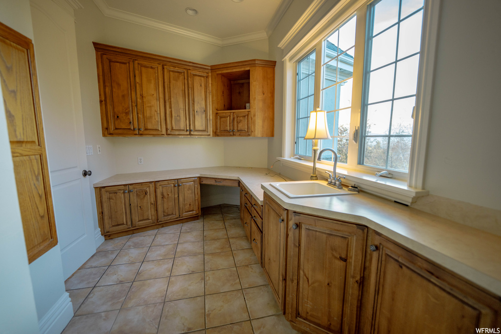 Kitchen with light tile flooring, sink, and crown molding