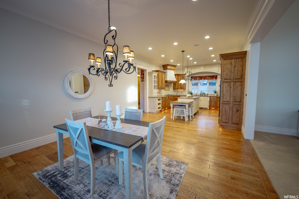 Dining space featuring light hardwood / wood-style flooring, a chandelier, and crown molding