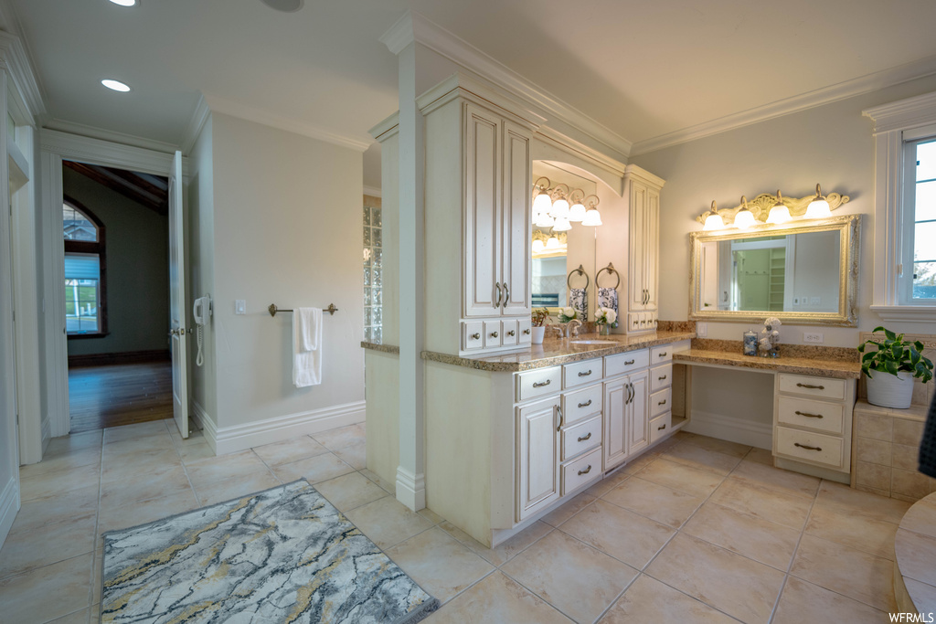 Bathroom featuring ornamental molding, hardwood / wood-style flooring, dual sinks, and vanity with extensive cabinet space
