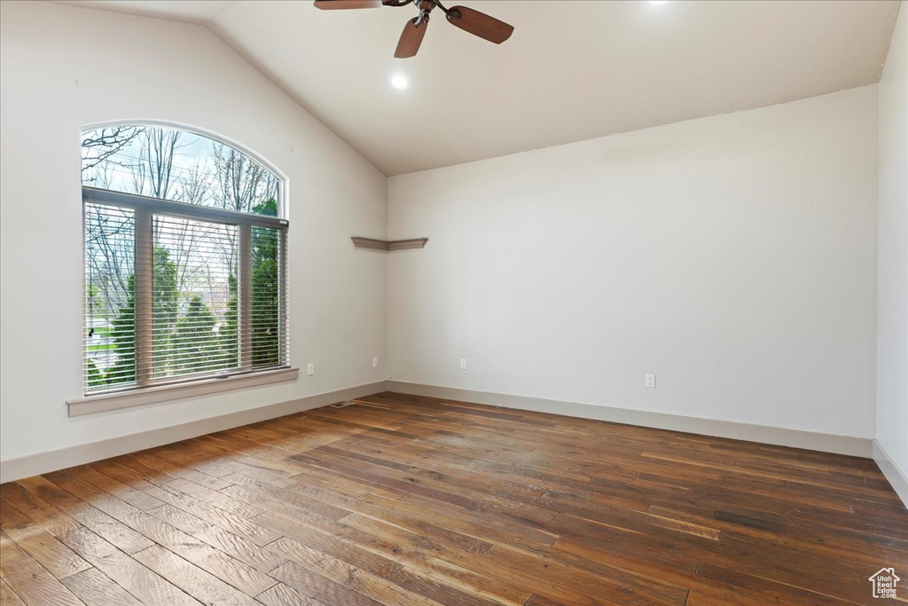 Empty room with dark wood-type flooring, ceiling fan, and lofted ceiling