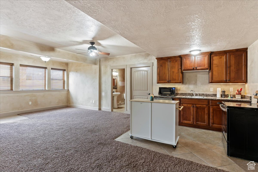 Kitchen featuring sink, ceiling fan, light tile floors, and a textured ceiling