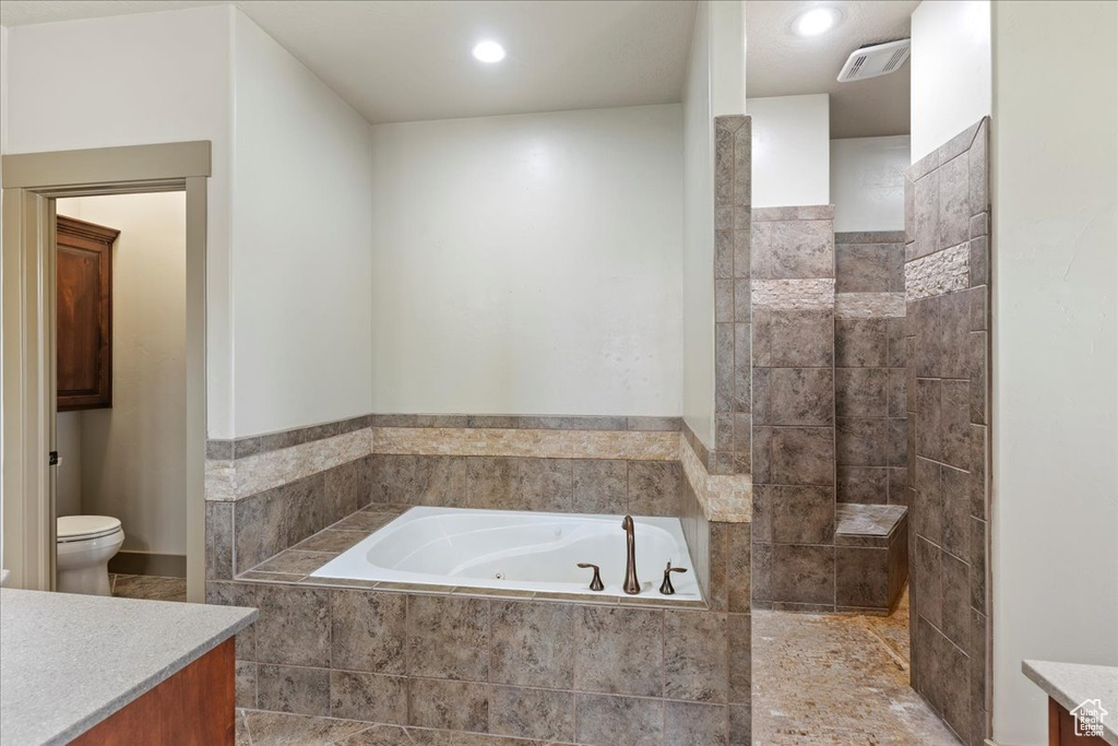 Bathroom with vanity, tile floors, toilet, and tiled bath