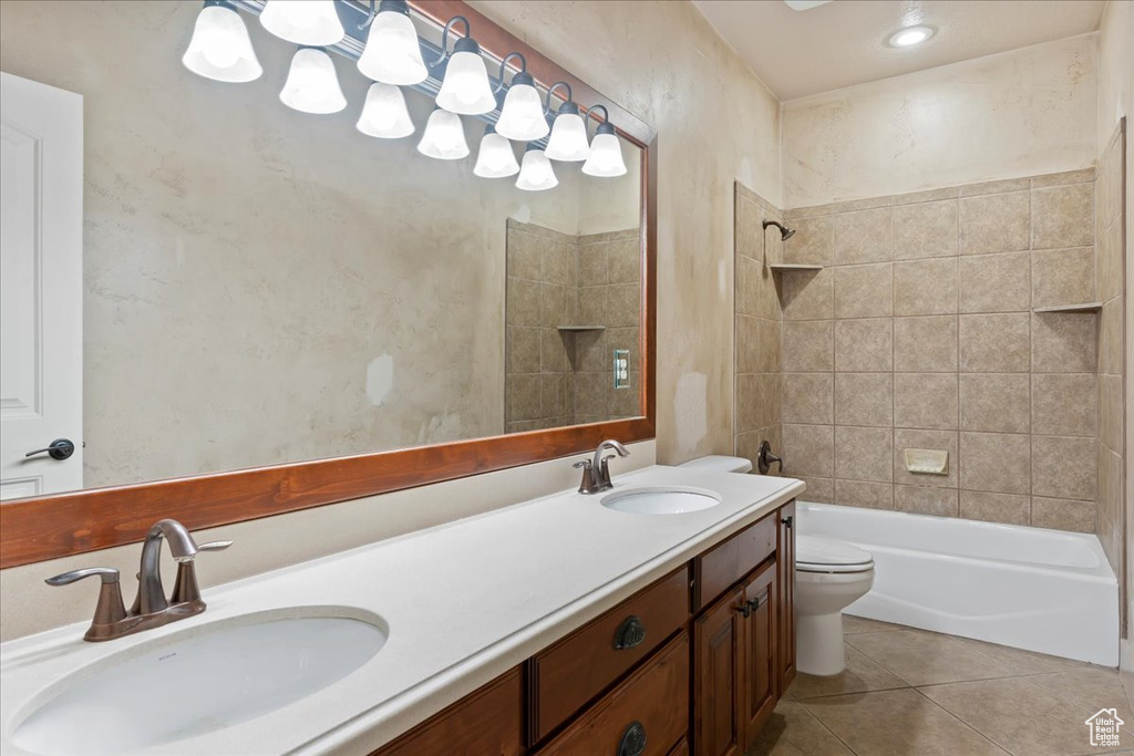 Full bathroom featuring tiled shower / bath, double sink, oversized vanity, tile flooring, and toilet