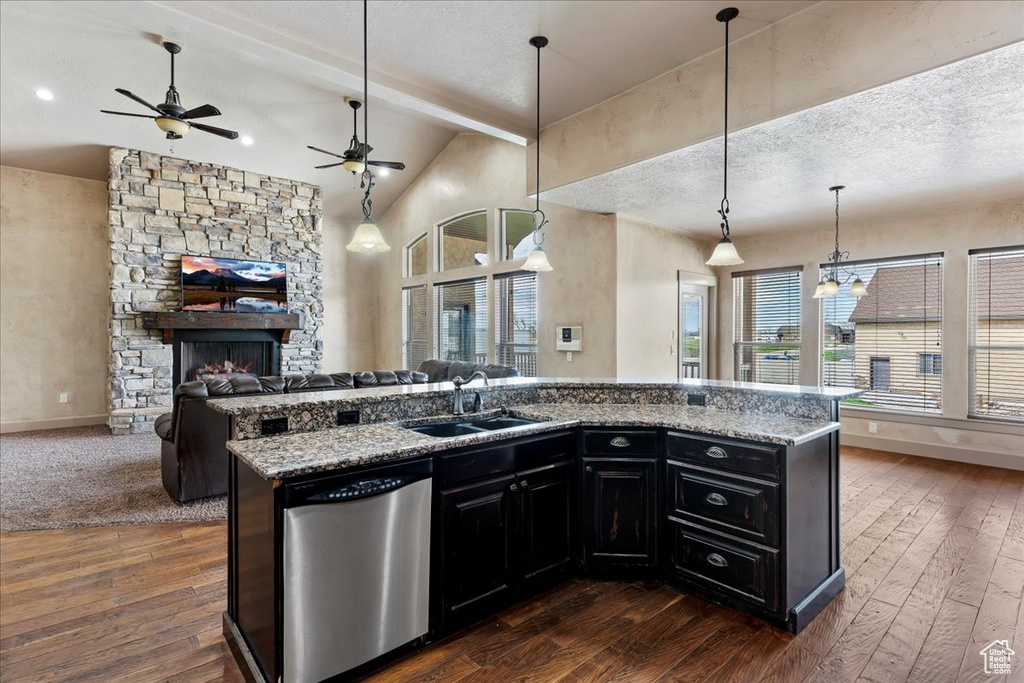 Kitchen featuring a stone fireplace, ceiling fan, dishwasher, sink, and pendant lighting