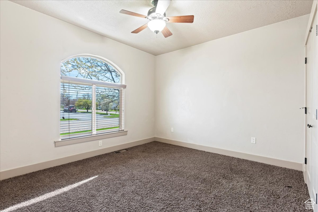 Empty room featuring a textured ceiling, ceiling fan, and carpet