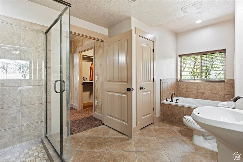 Bathroom featuring shower with separate bathtub, tile floors, and a textured ceiling