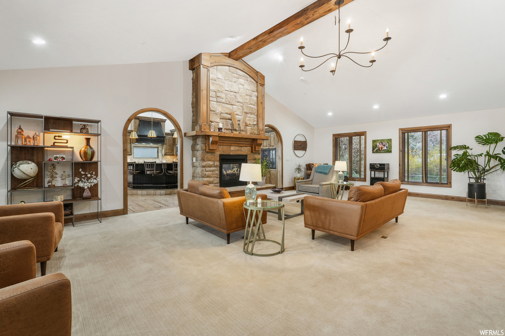Living room featuring a fireplace, an inviting chandelier, high vaulted ceiling, light colored carpet, and beam ceiling