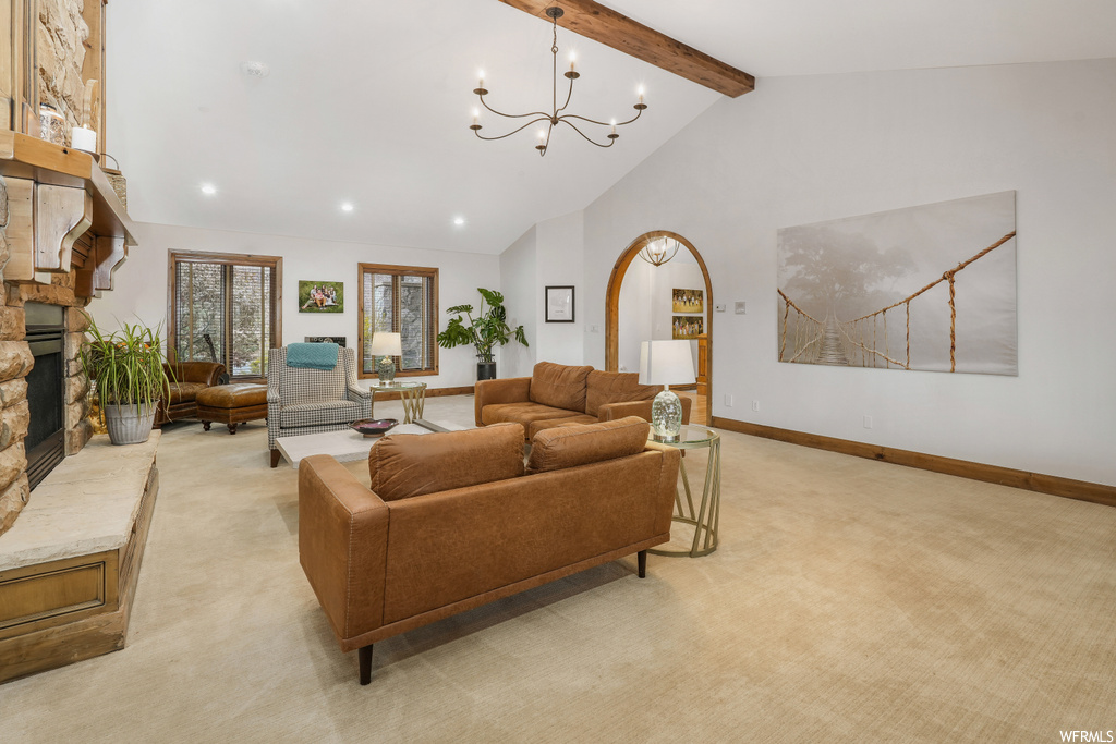 Carpeted living room featuring an inviting chandelier, a fireplace, high vaulted ceiling, and beamed ceiling