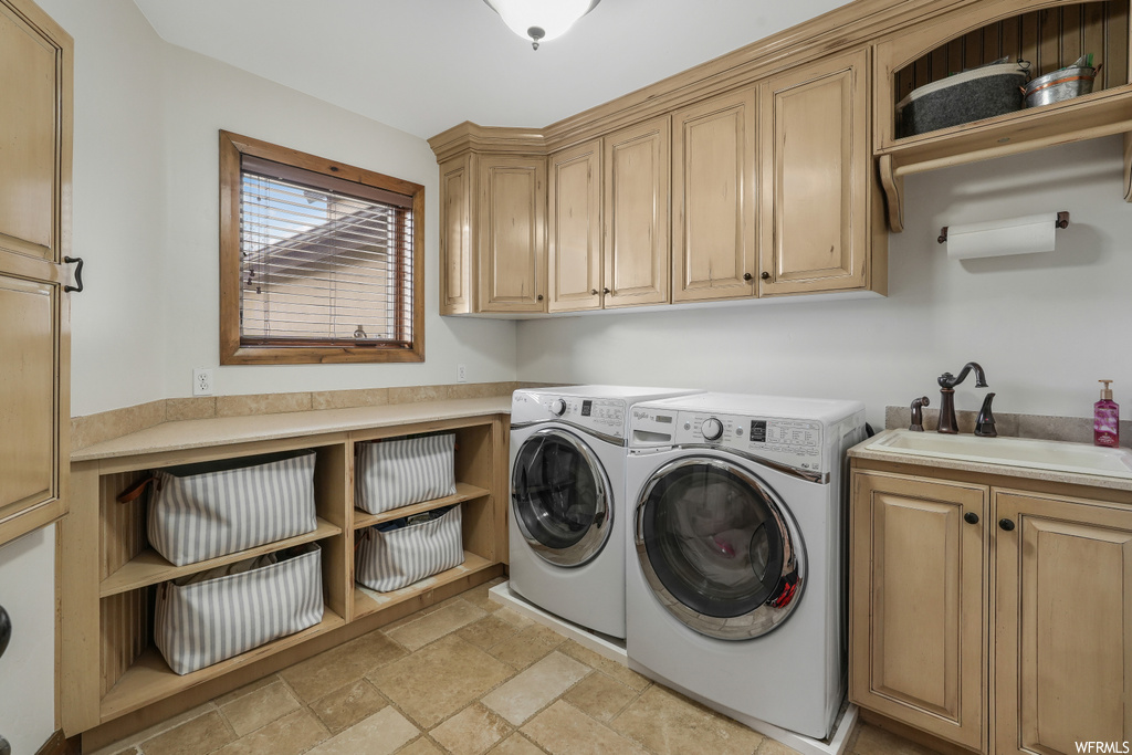 Clothes washing area featuring cabinets, sink, light tile flooring, and washer and dryer