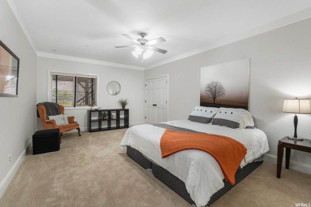 Bedroom featuring ornamental molding, a closet, ceiling fan, and light colored carpet