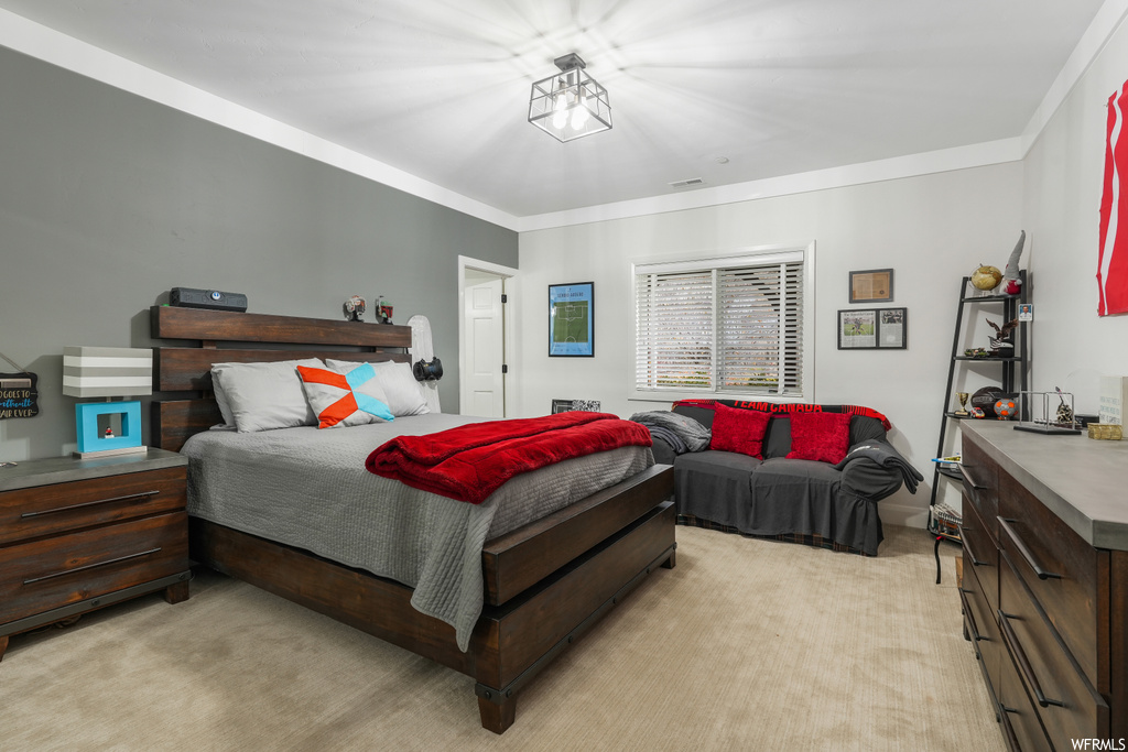 Bedroom featuring ornamental molding, light carpet, and a chandelier