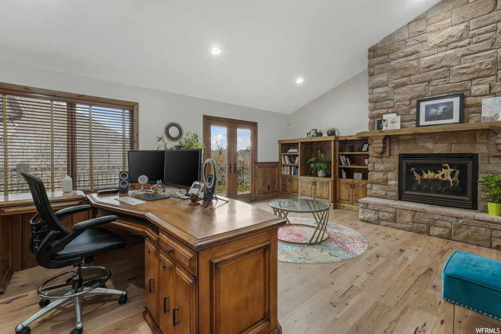 Office area featuring a fireplace, vaulted ceiling, light hardwood / wood-style floors, and french doors