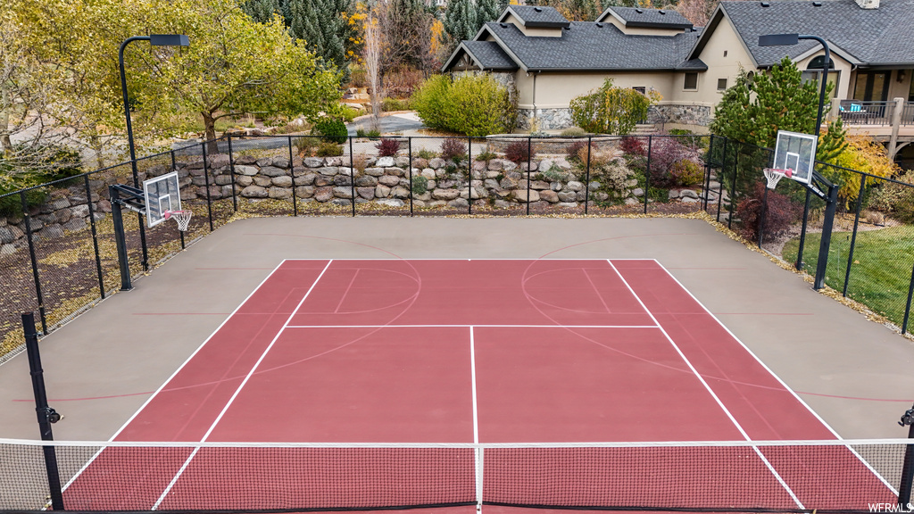 View of tennis court featuring basketball hoop