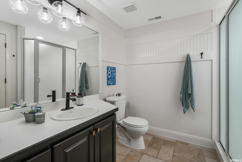 Bathroom featuring toilet, walk in shower, tile floors, and large vanity