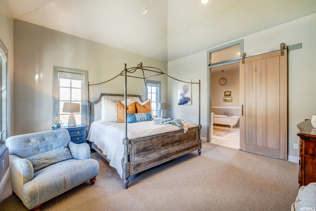 Carpeted bedroom featuring a barn door and ensuite bath