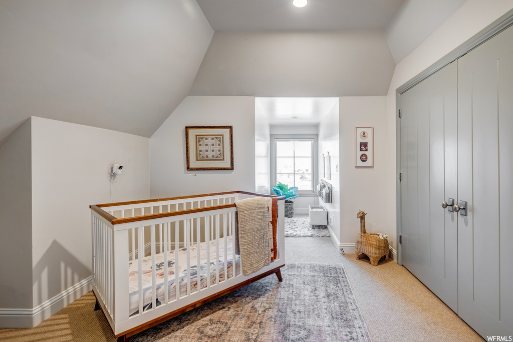 Carpeted bedroom with lofted ceiling, a closet, and a nursery area