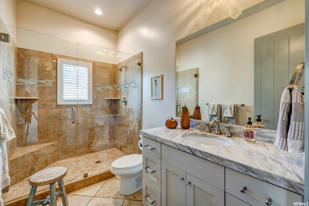 Bathroom with toilet, a shower with shower door, tile floors, and large vanity