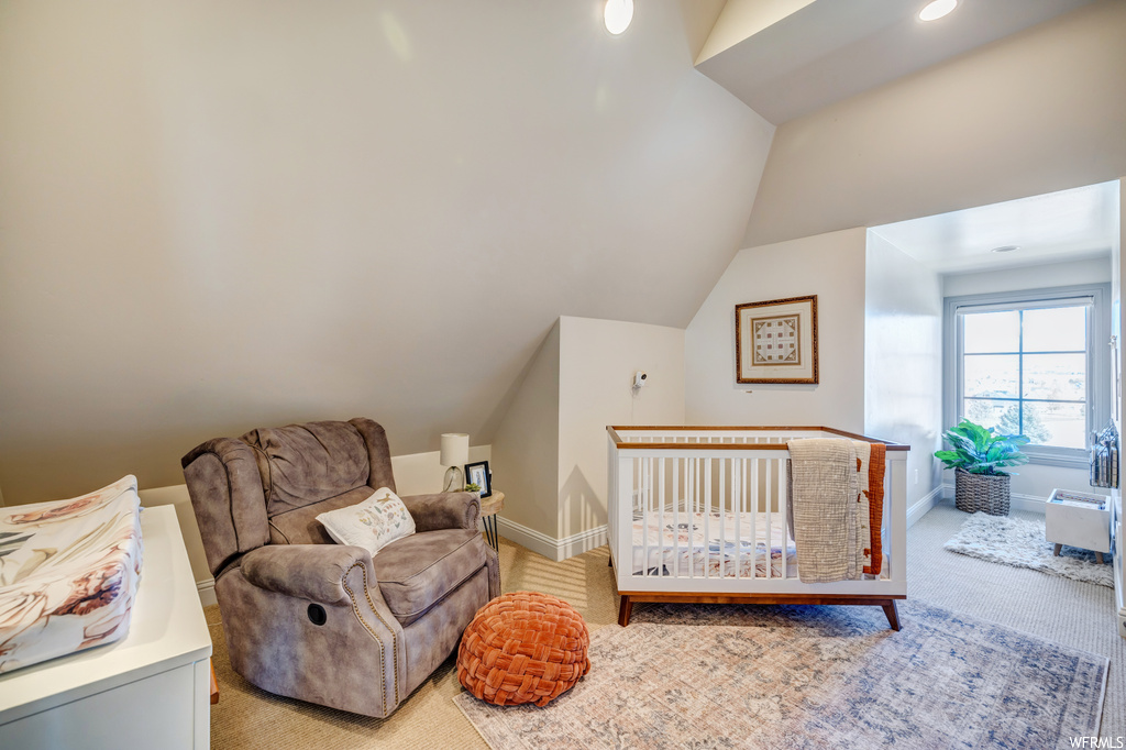 Bedroom with light carpet, vaulted ceiling, and a nursery area