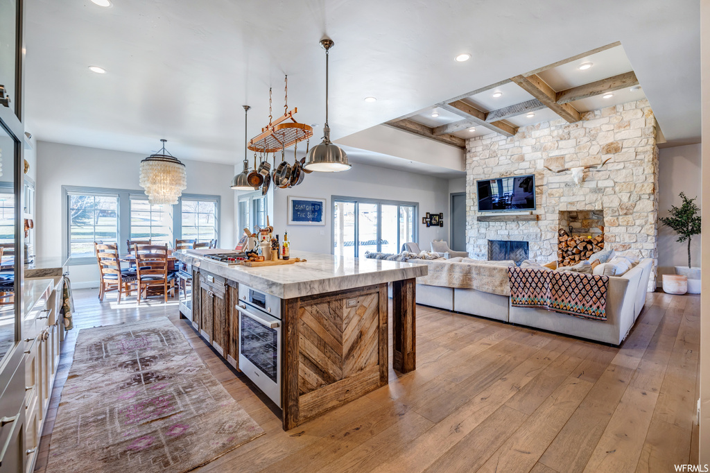 Kitchen featuring a kitchen island with sink, coffered ceiling, beam ceiling, and decorative light fixtures