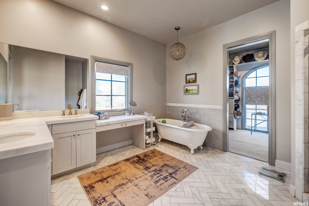 Bathroom with a healthy amount of sunlight, a bathtub, tile flooring, and dual bowl vanity