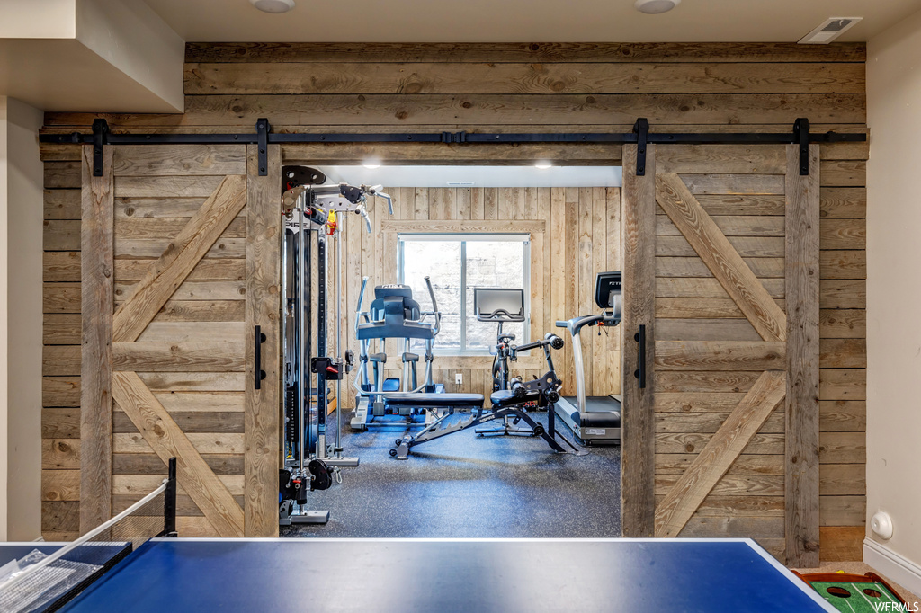 Exercise room featuring a barn door and wooden walls