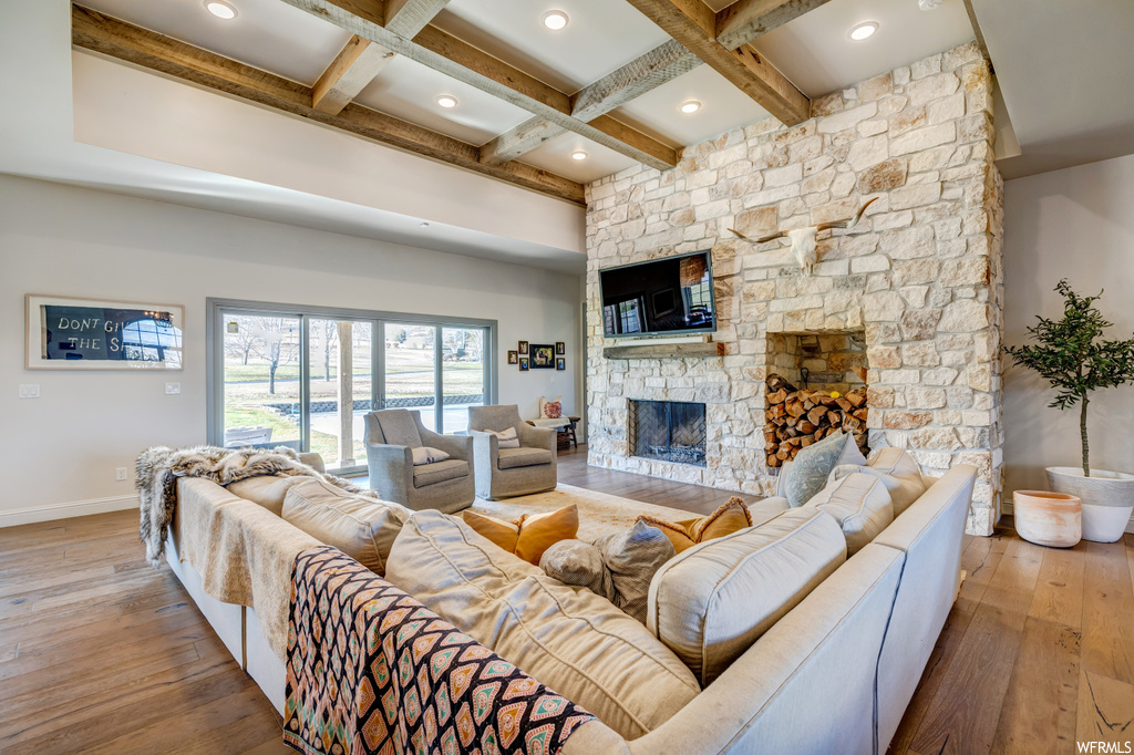 Living room featuring light hardwood / wood-style flooring, beamed ceiling, a fireplace, and coffered ceiling