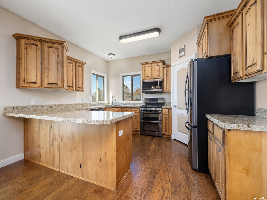 Kitchen with dark hardwood / wood-style floors, sink, stainless steel appliances, and kitchen peninsula