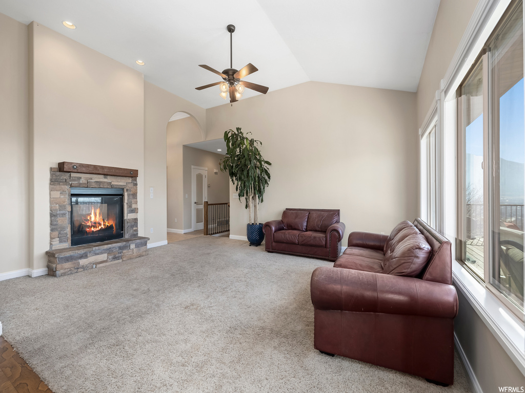 Living room featuring light colored carpet, ceiling fan, a fireplace, and vaulted ceiling