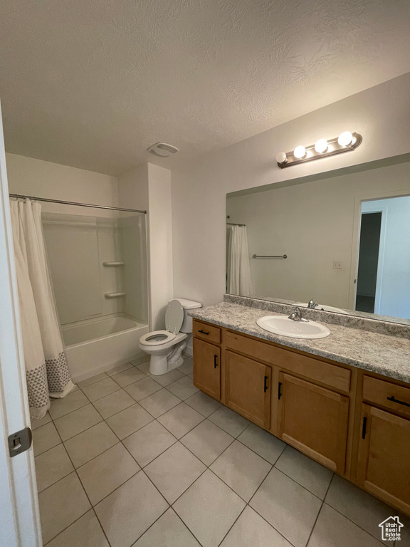Full bathroom featuring vanity, tile floors, a textured ceiling, toilet, and shower / bath combination with curtain