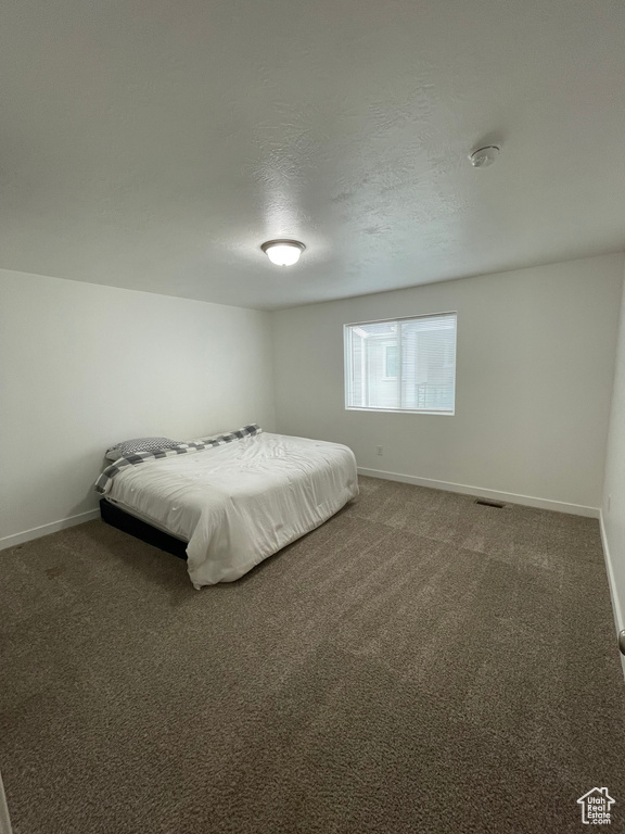 Unfurnished bedroom featuring dark carpet