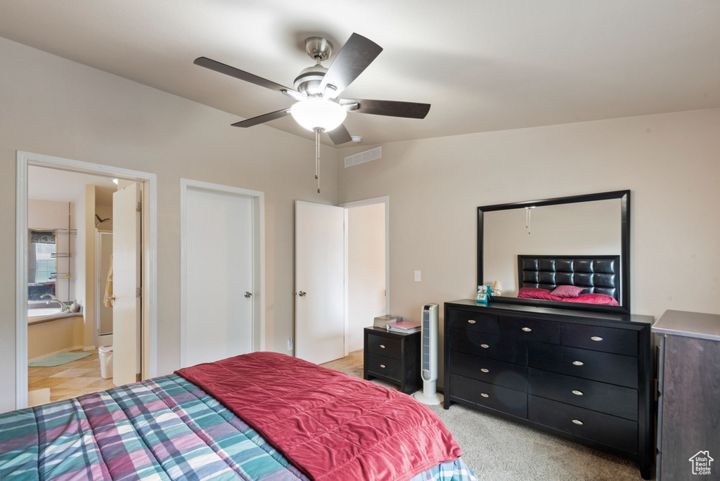 Bedroom featuring light carpet, connected bathroom, and ceiling fan