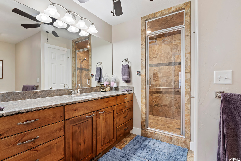 Bathroom featuring ceiling fan, walk in shower, and vanity