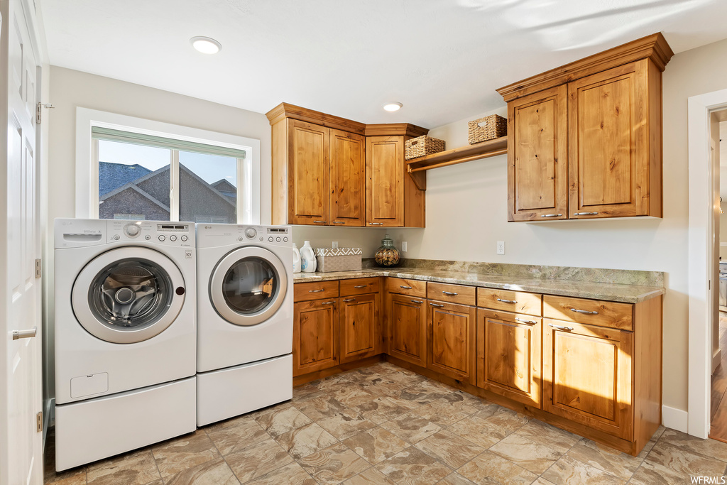 Laundry area featuring independent washer and dryer, cabinets, and light tile flooring