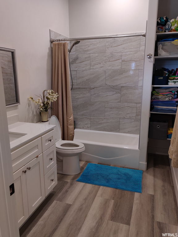 Full bathroom featuring toilet, shower / tub combo, wood-type flooring, and vanity
