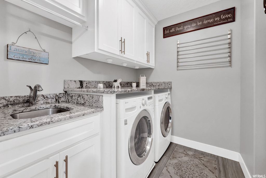 Laundry room with cabinets, independent washer and dryer, light tile flooring, and sink