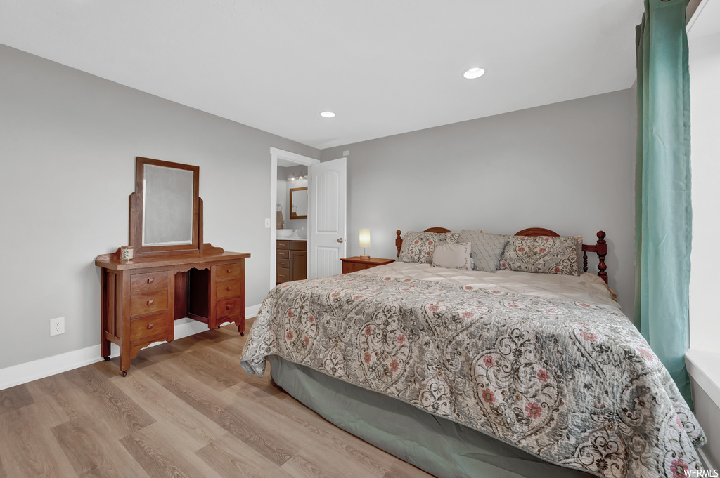 Bedroom with ensuite bathroom and light hardwood / wood-style floors