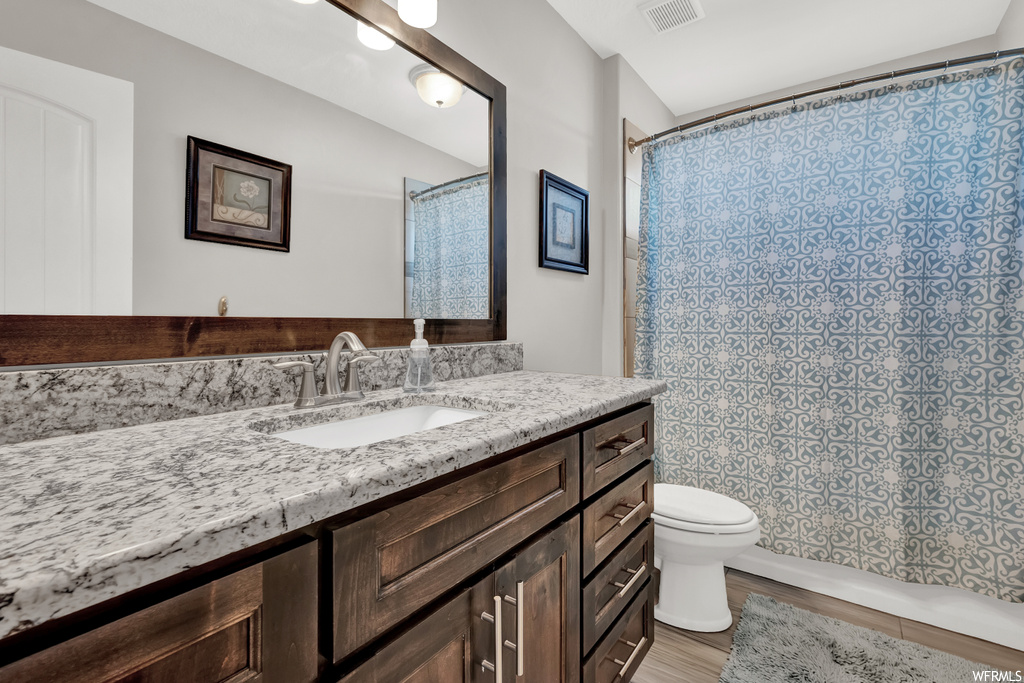 Full bathroom with toilet, large vanity, and shower / bathtub combination with curtain