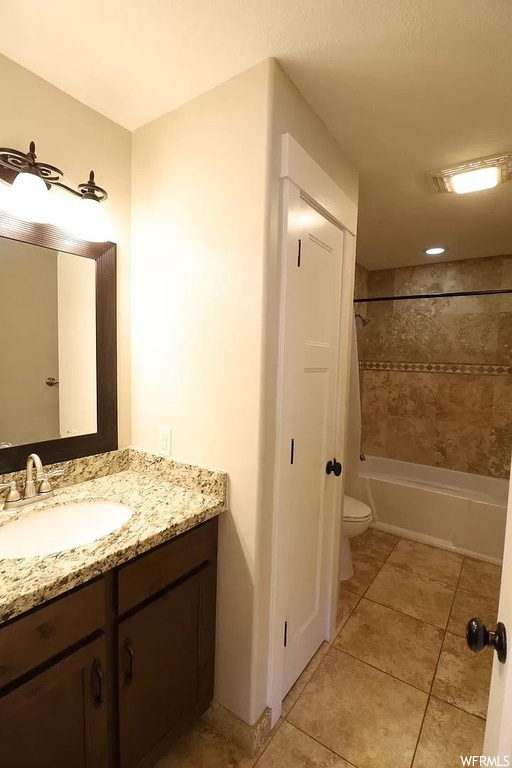 Full bathroom with toilet, washtub / shower combination, tile flooring, and large vanity