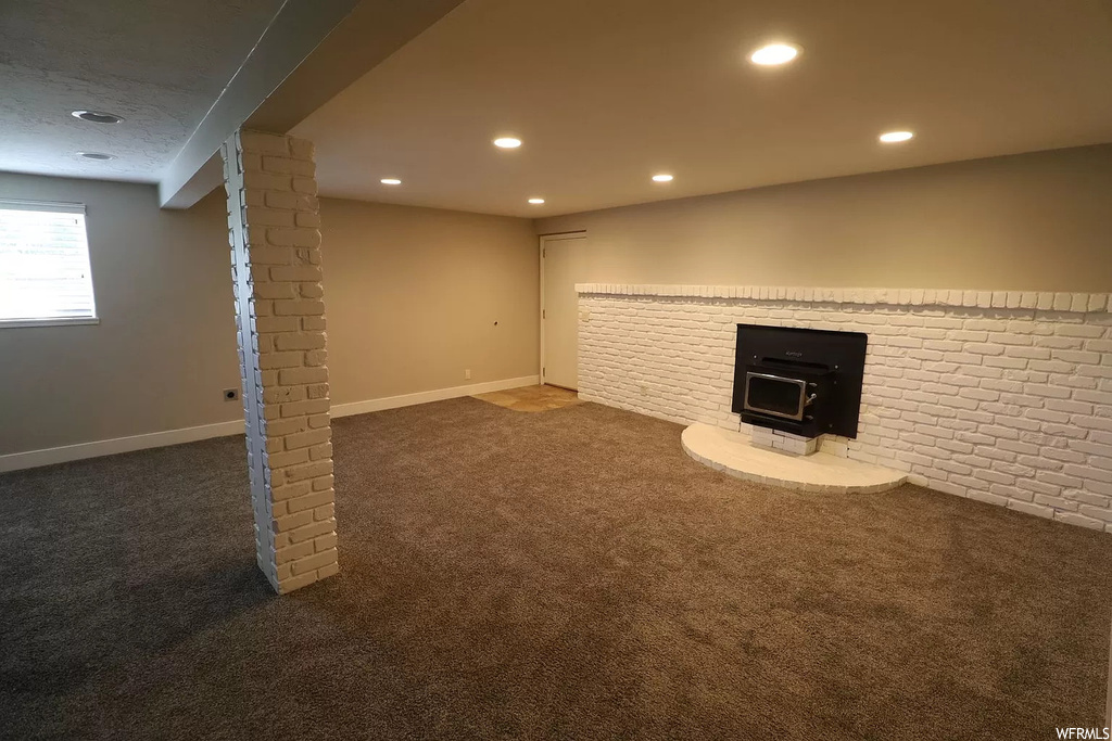 Unfurnished living room featuring dark carpet, a wood stove, and a fireplace