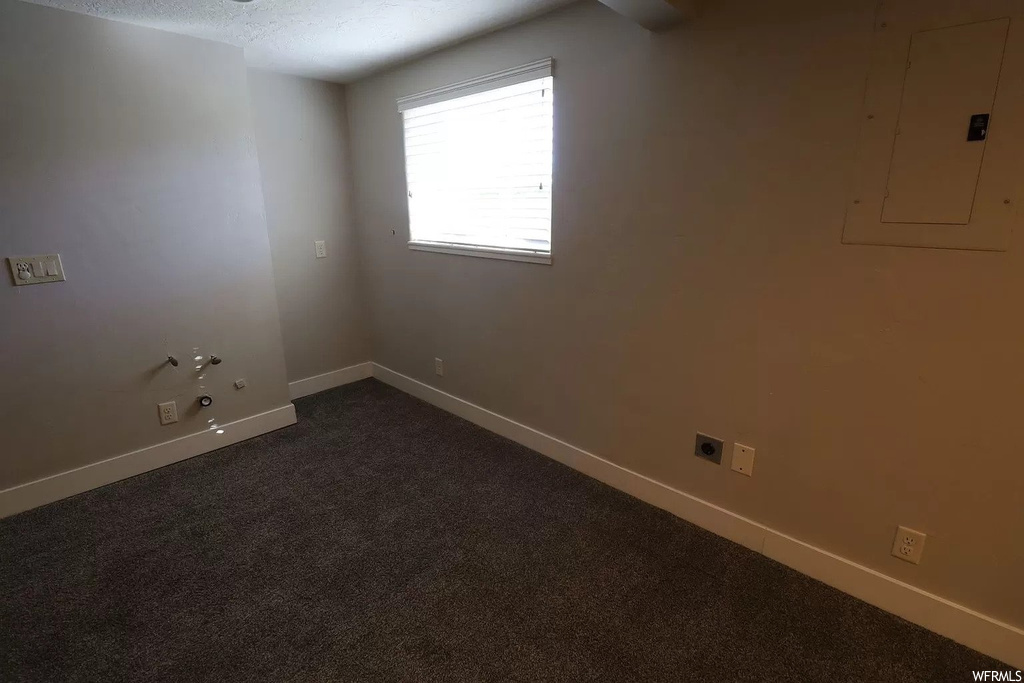 Spare room featuring dark colored carpet and a textured ceiling