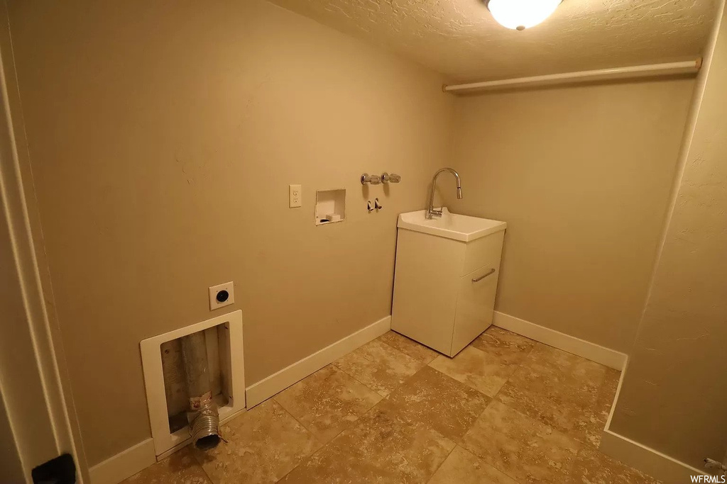 Clothes washing area with washer hookup and light tile floors